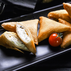 Some pieces of ALKARAMAH Sambosah, Sambosa along with a tomato