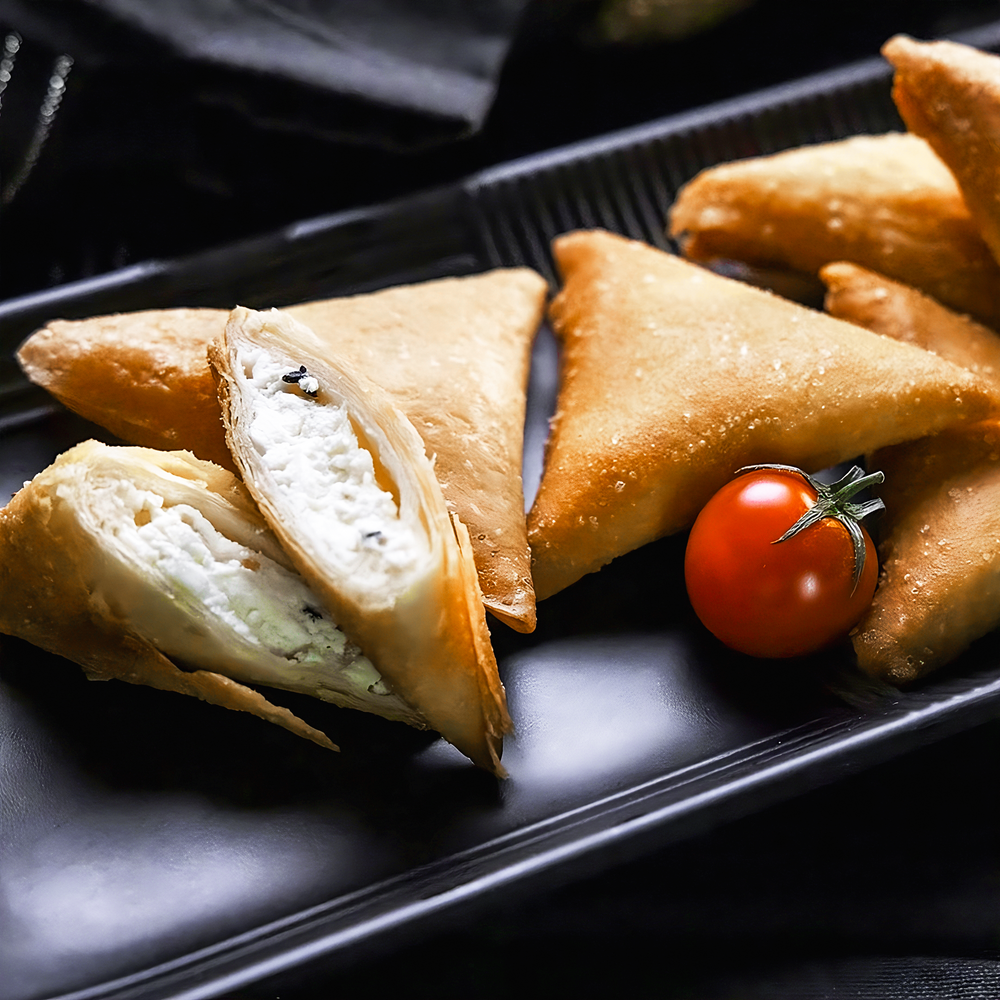 Some pieces of ALKARAMAH Sambosah, Sambosa along with a tomato