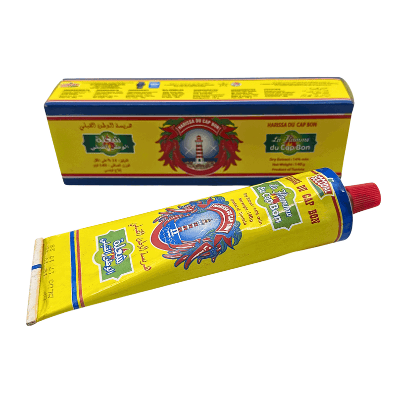 Authentic Harissa Du Cap Bon Tunisian chili paste in 140g tube, spicy red pepper with garlic and caraway, shown in lifestyle setting.